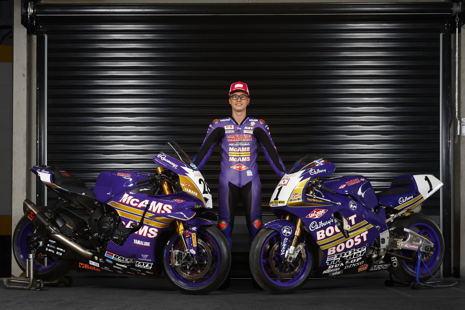 Bradley Ray de pie con su McAMS Yamaha y la bicicleta Cadbury Boost original.